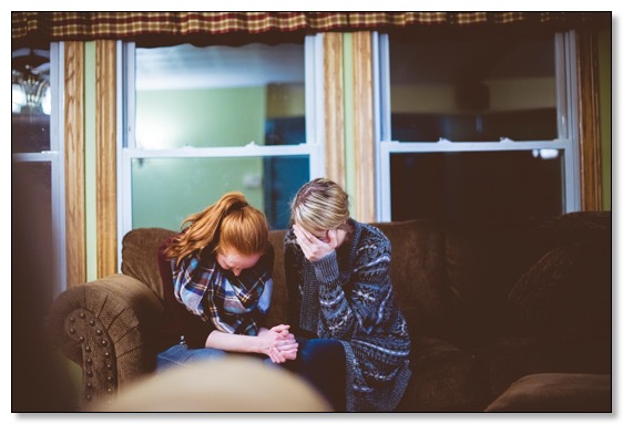 Picture of a mother and daughter sitting on a couch crying, communicating the need for training and support for dementia. 